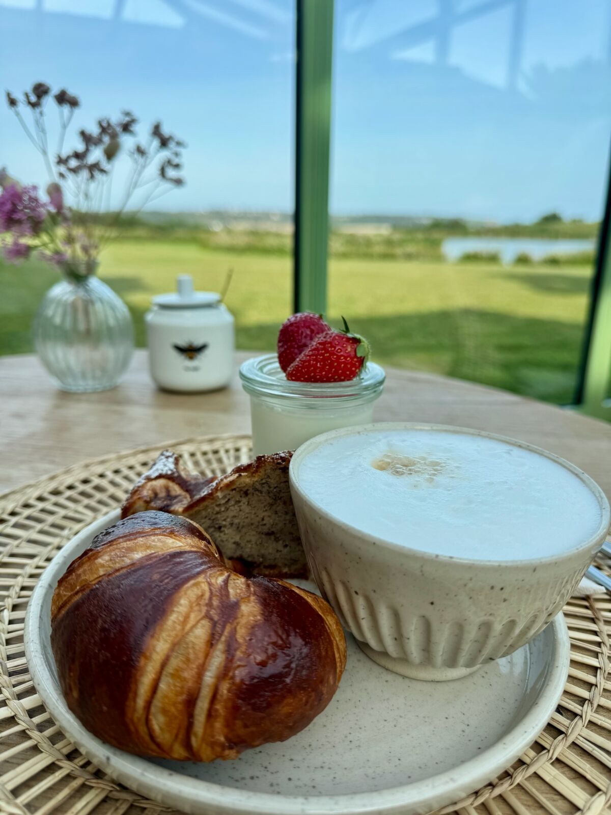 Croissant, cake and cappuccino with a view over the garden